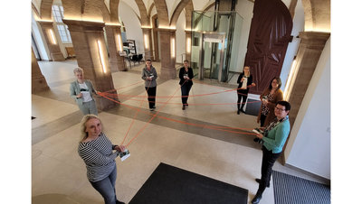 Vertreterinnen des Arbeitskreises Sucht spannen mit Hilfe eines orangen Seils ein symbolisches Netz für die Veröffentlichung des ersten Suchtwegweisers im Landkreis Eichsfeld.